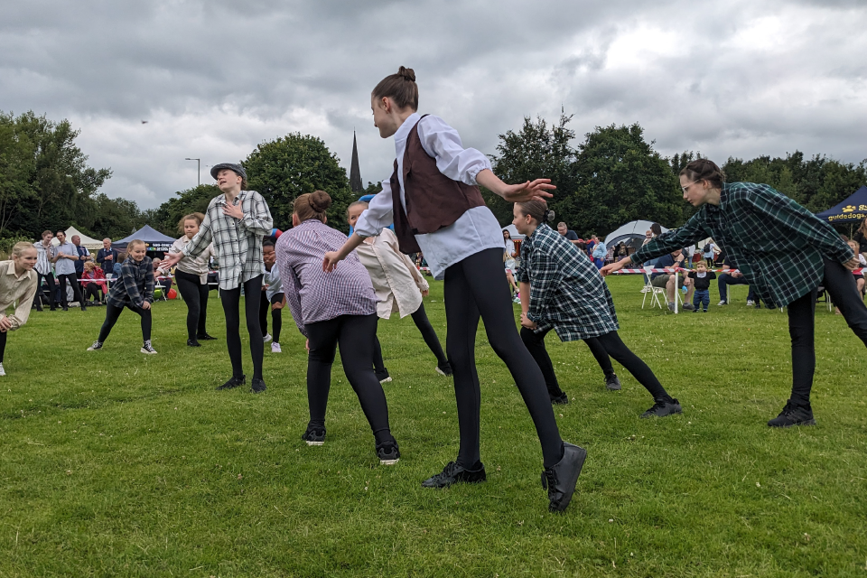 Photo of a dance troup. performing on a field. 