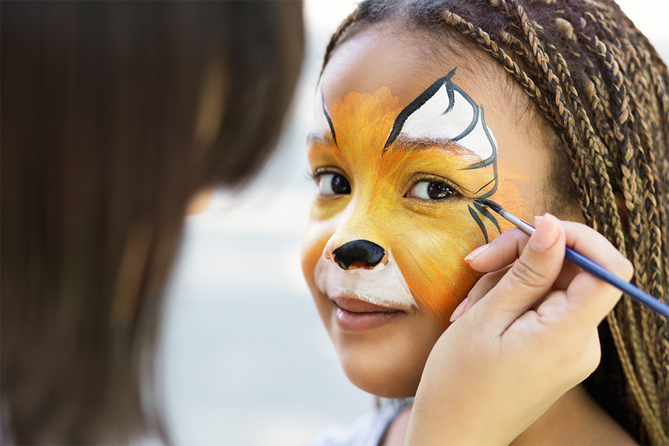 Young black girl having her face painted.