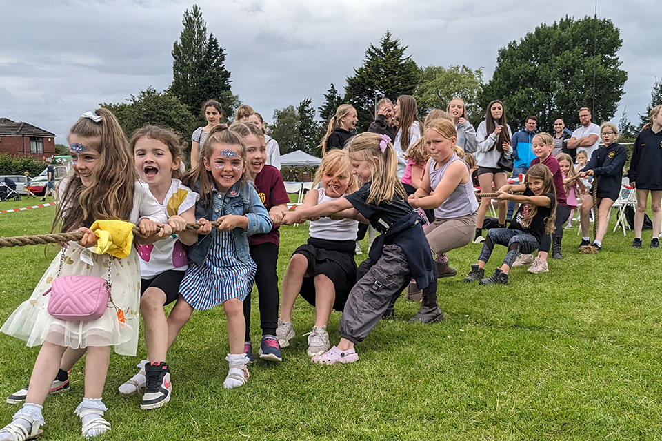 A group of young girls tugging on a rope during a game of tug of war. 