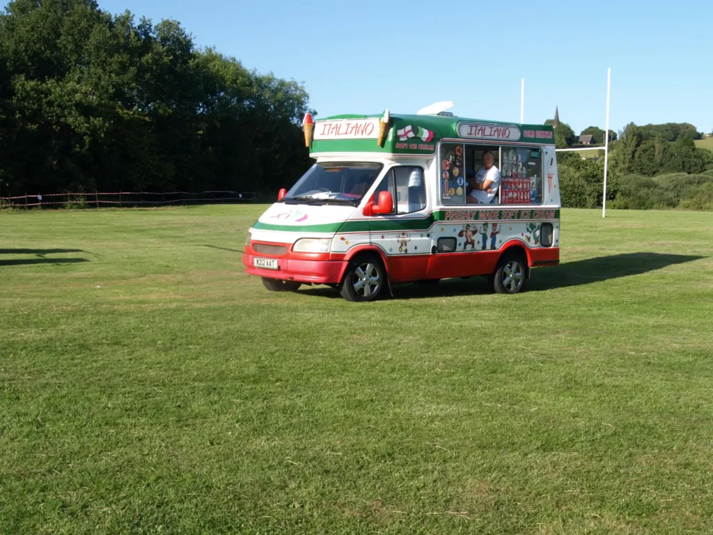 Ice cream van parked on Alder Lane Playing Fields during the Parbold Village Show Friday Night Disco 2025, with trees and countryside in the background.