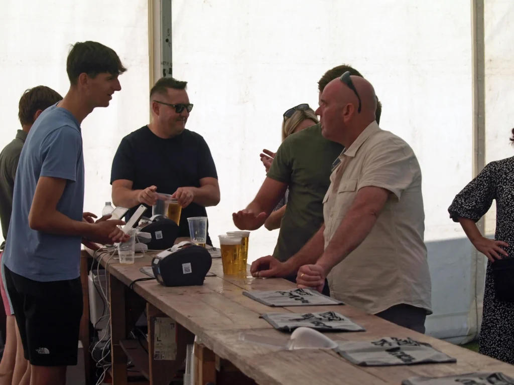 Friendly staff serving pints of beer from the bar inside the marquee at the Parbold Village Show Friday Night Disco 2025.