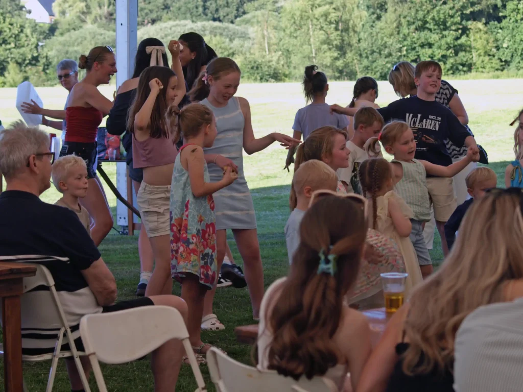 Children dancing together and having fun under the marquee at the Parbold Village Show Friday Night Disco 2025, with adults seated at tables in the background.