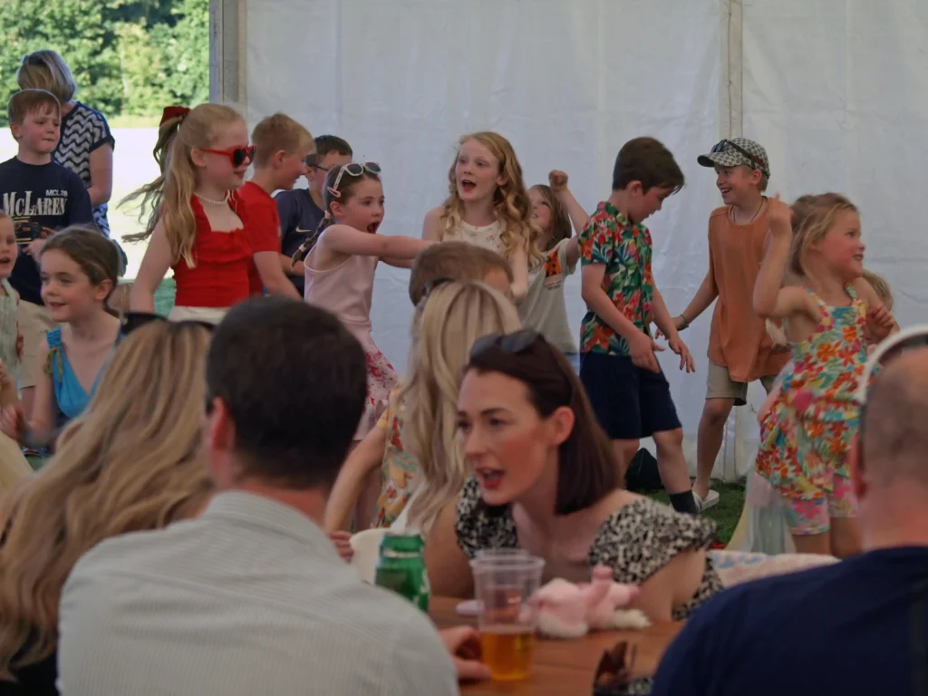 Lively group of children dancing and playing during the Parbold Village Show Friday Night Disco 2025, with adults enjoying the atmosphere nearby.