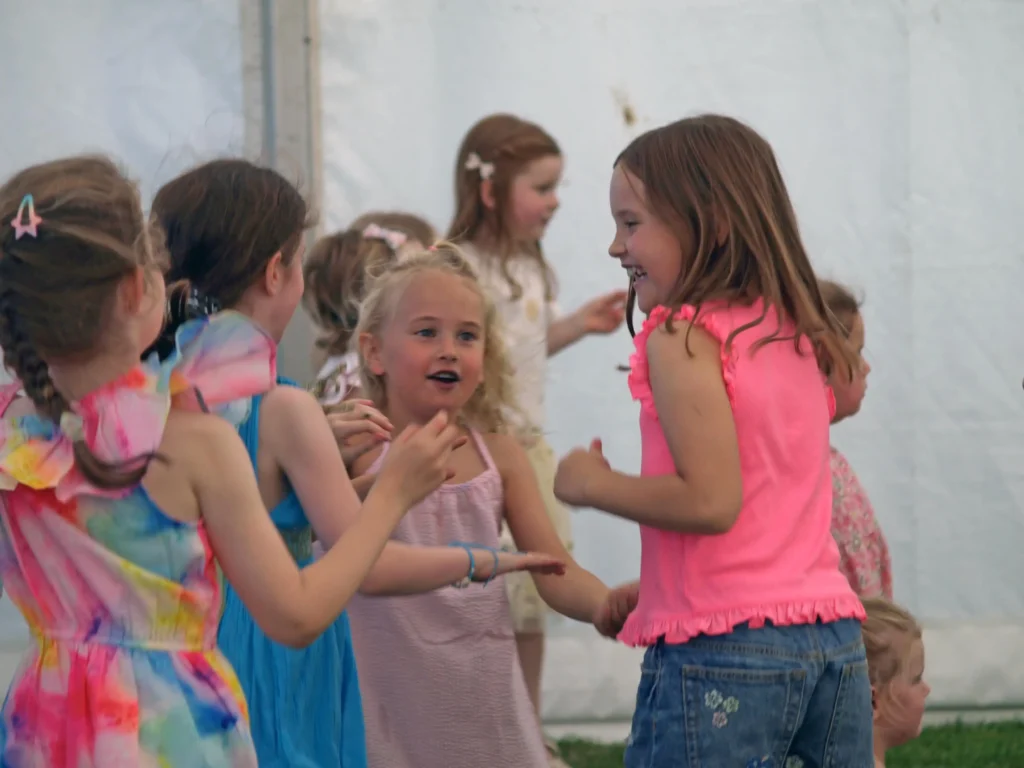 Close-up of young children smiling and chatting while dancing inside the marquee at the Parbold Village Show Friday Night Disco 2025.