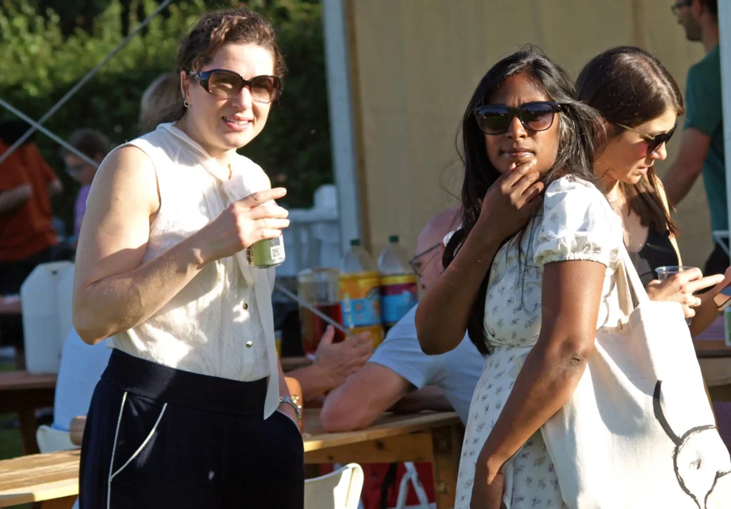 Two women enjoying a drink and chatting in the sunshine at the Parbold Village Show Friday Night Disco 2025, with guests and refreshments in the background.