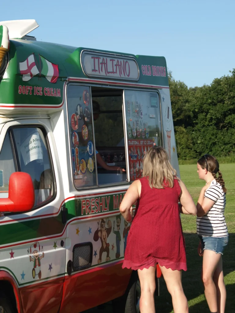 Woman and girl ordering from an ice cream van on a sunny evening at the Parbold Village Show Friday Night Disco 2025.