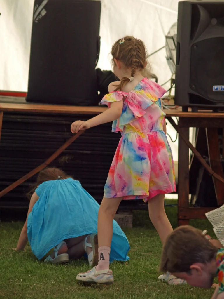 Young girl in a colourful dress playing near the stage during the Parbold Village Show Friday Night Disco 2025.
