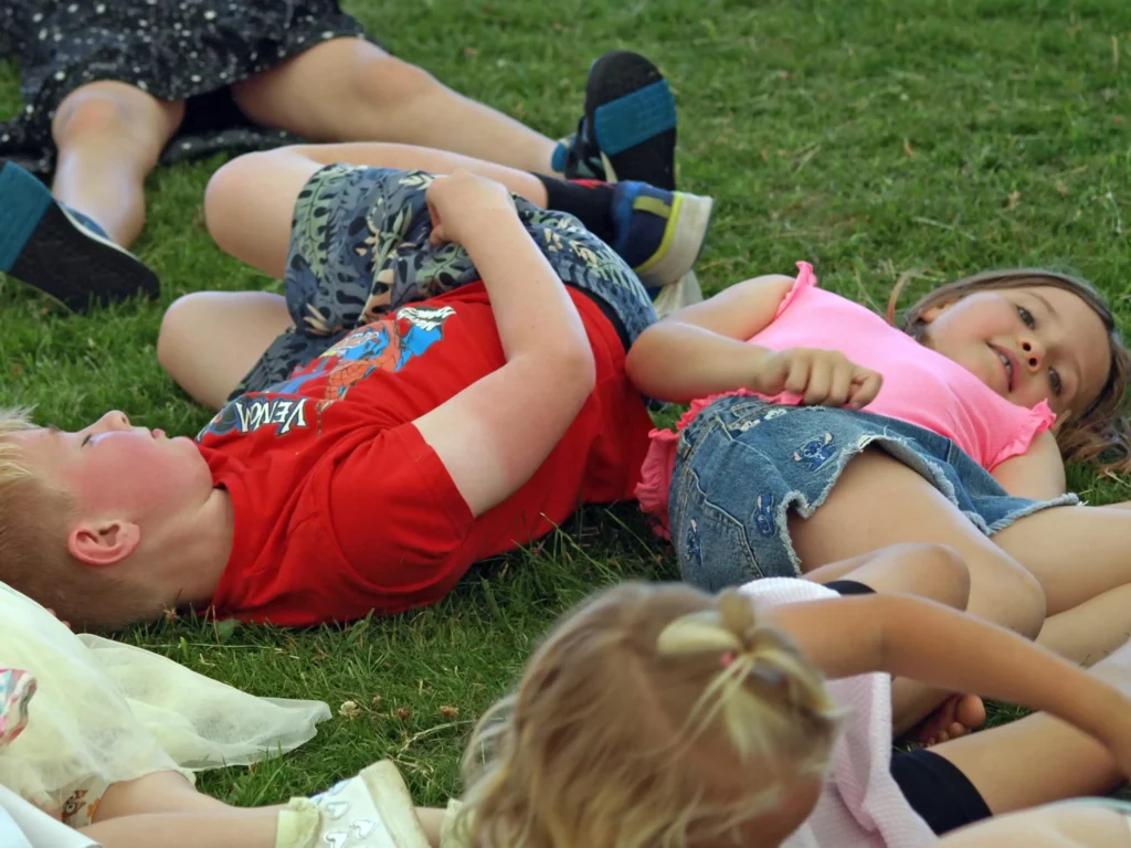 Children lying down and giggling during a group activity on the grass inside the marquee at the Parbold Village Show Friday Night Disco 2025.