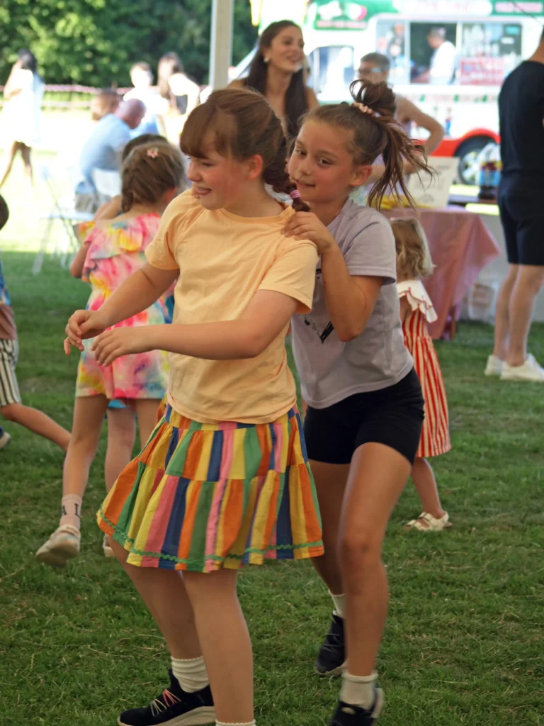 Children dancing in a conga line inside the marquee at the Parbold Village Show Friday Night Disco 2025, with colourful summer outfits.