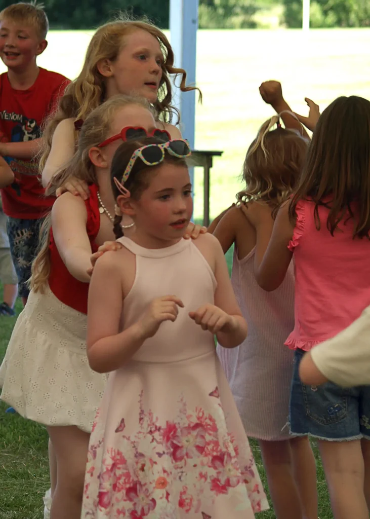 Close-up of children dancing in a lively conga line at the Parbold Village Show Friday Night Disco 2025, under the marquee.