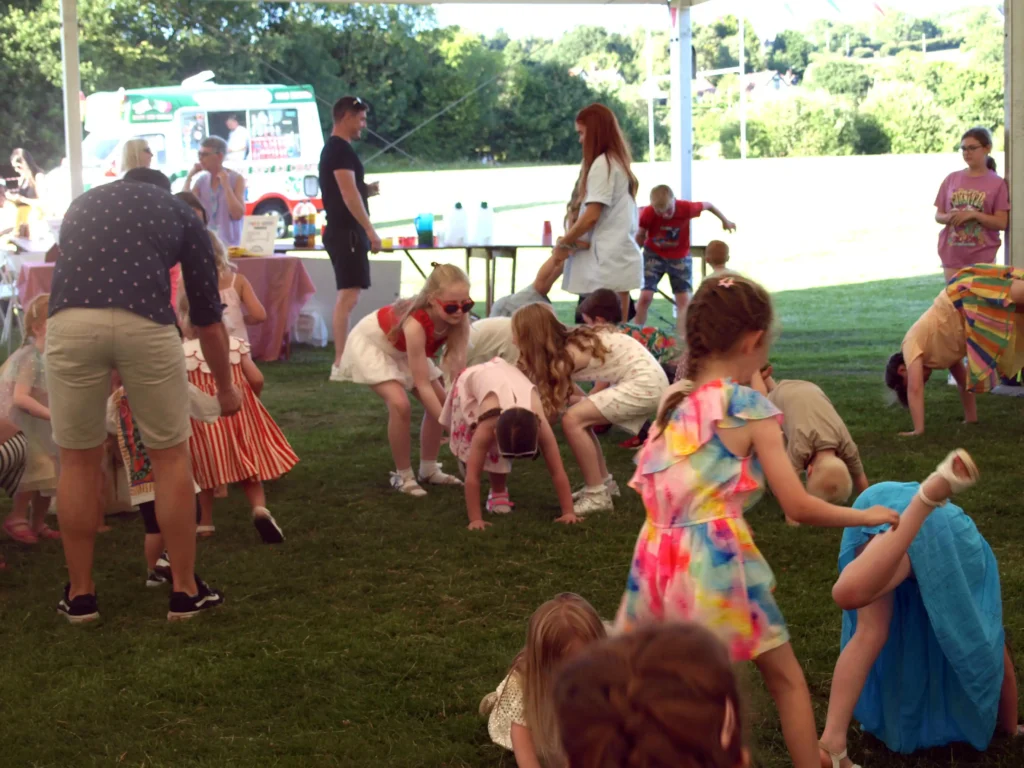 Colourful crowd of children enjoying a movement-based game under the marquee at the Parbold Village Show Friday Night Disco 2025.