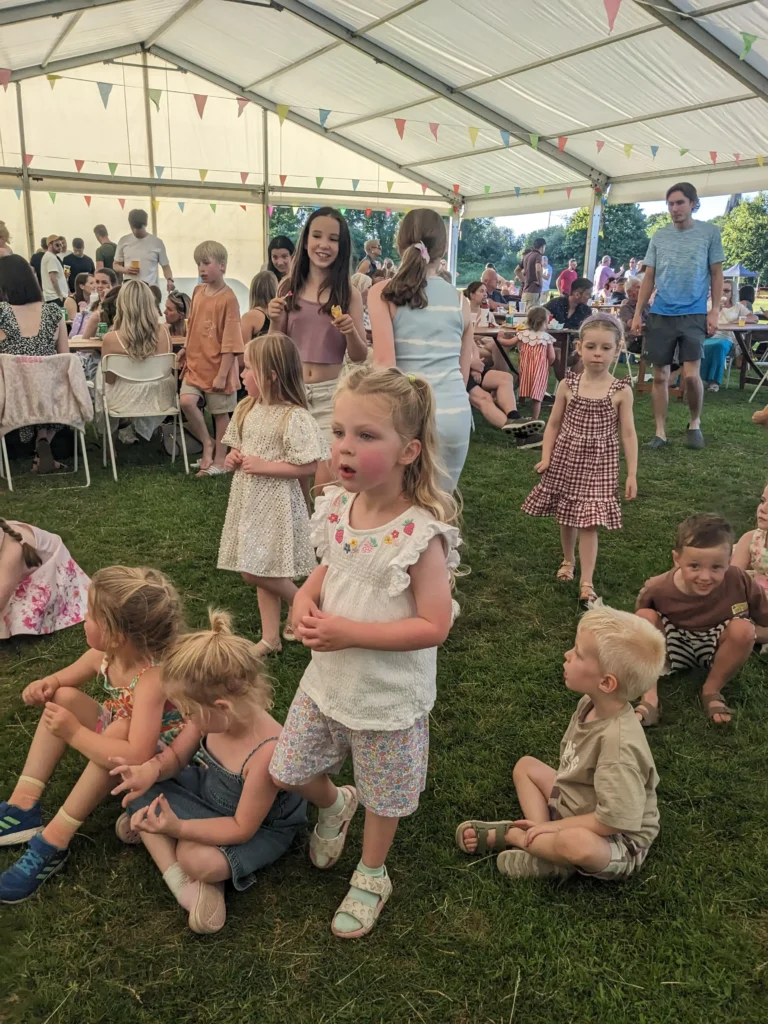 Children standing and sitting under the marquee at the Parbold Village Show Friday Night Disco 2025, enjoying music and games.