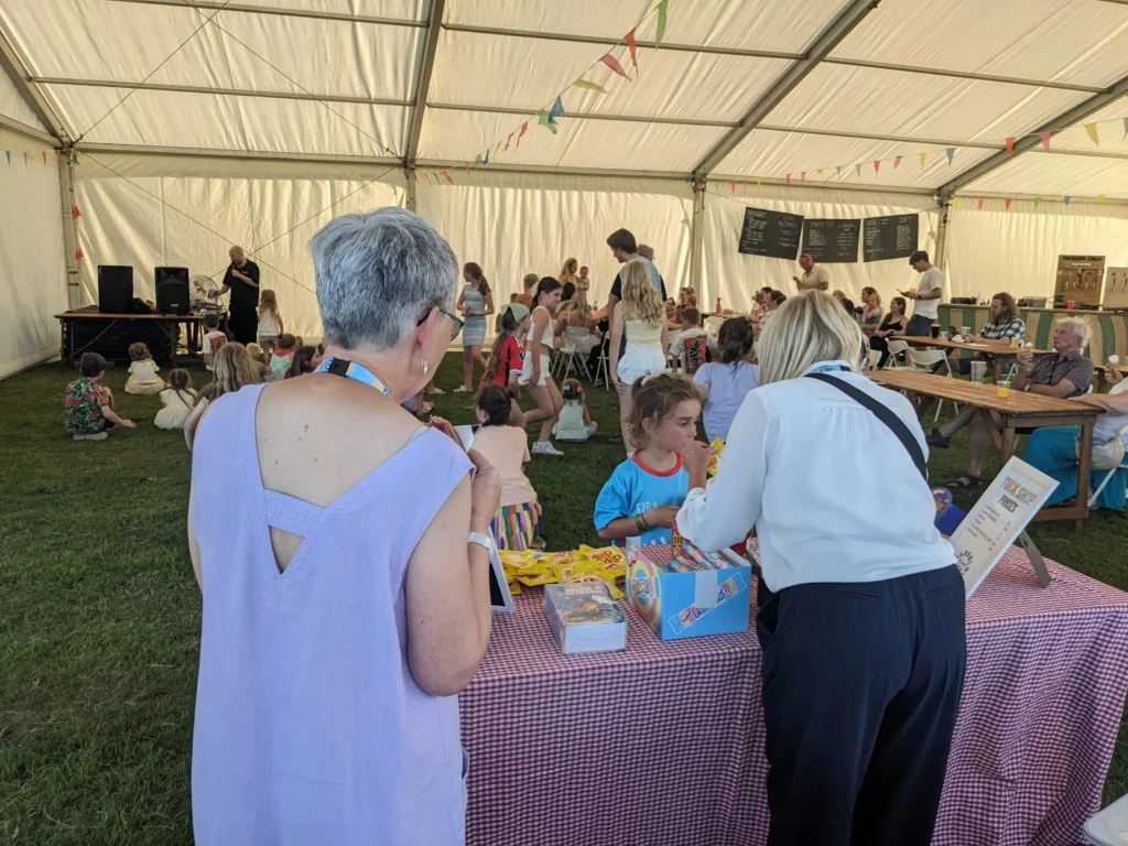 Busy tuck shop table with retro sweets and drinks inside the marquee at the Parbold Village Show Friday Night Disco 2025.